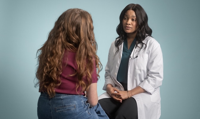 Back of woman and doctor in white coat having a discussion